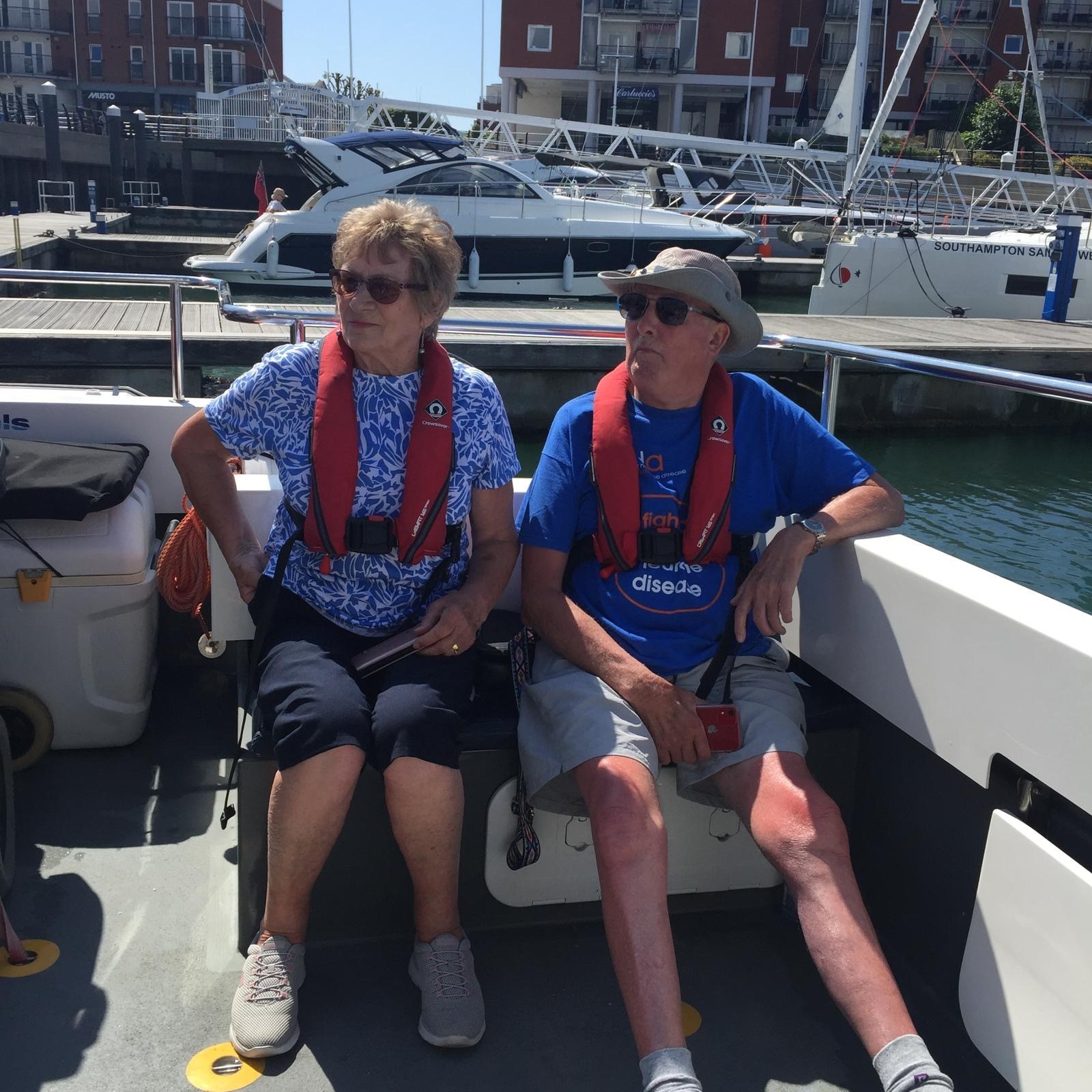 Two MND Association volunteers on a boat with life-jackets.
