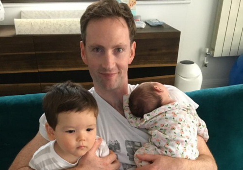 Eoin sitting on a sofa, with his two children