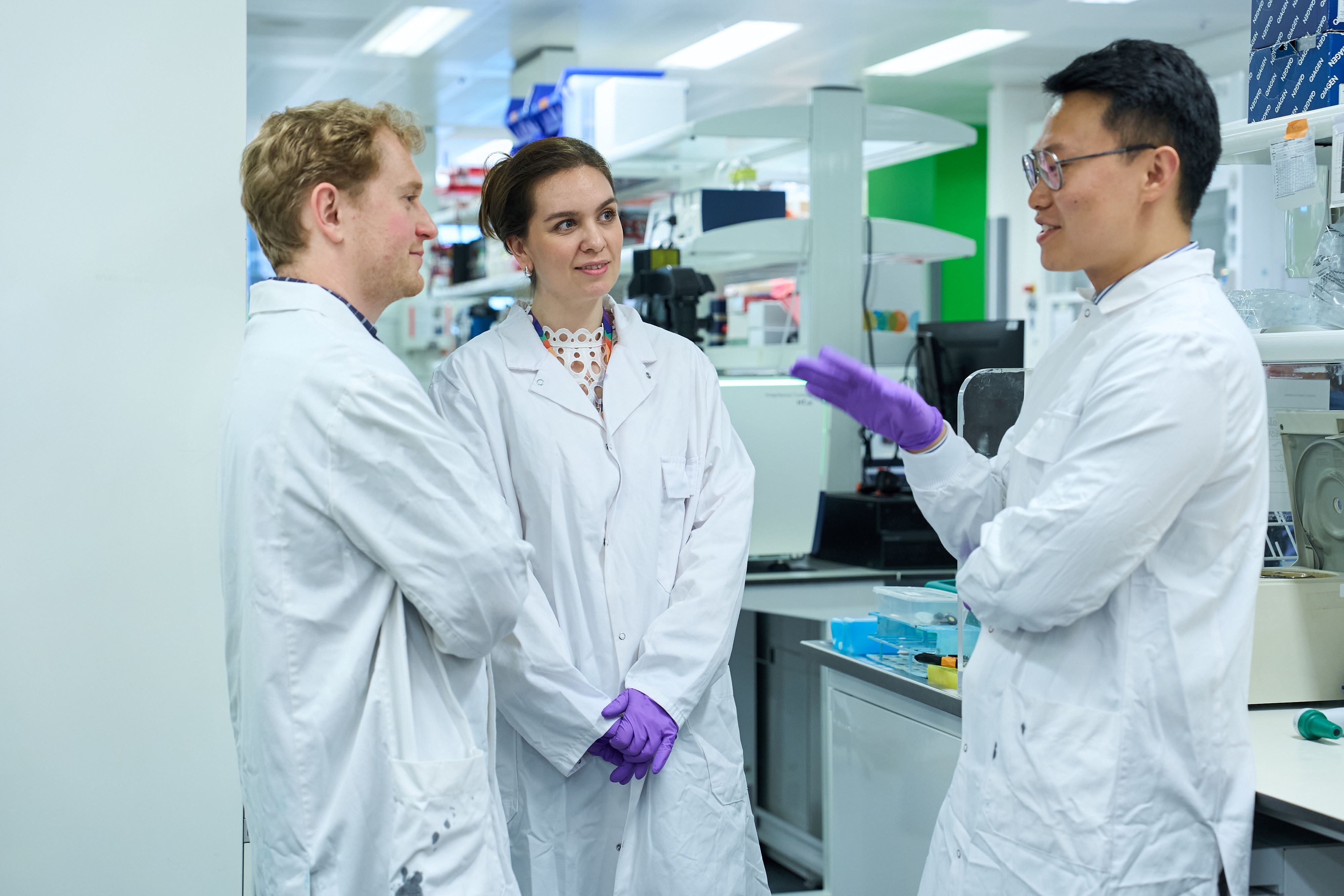 Three researchers in white lab coats having a discussion