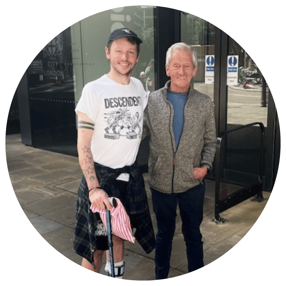 Jake and Peter standing outside an automatic door, smiling at the camera.