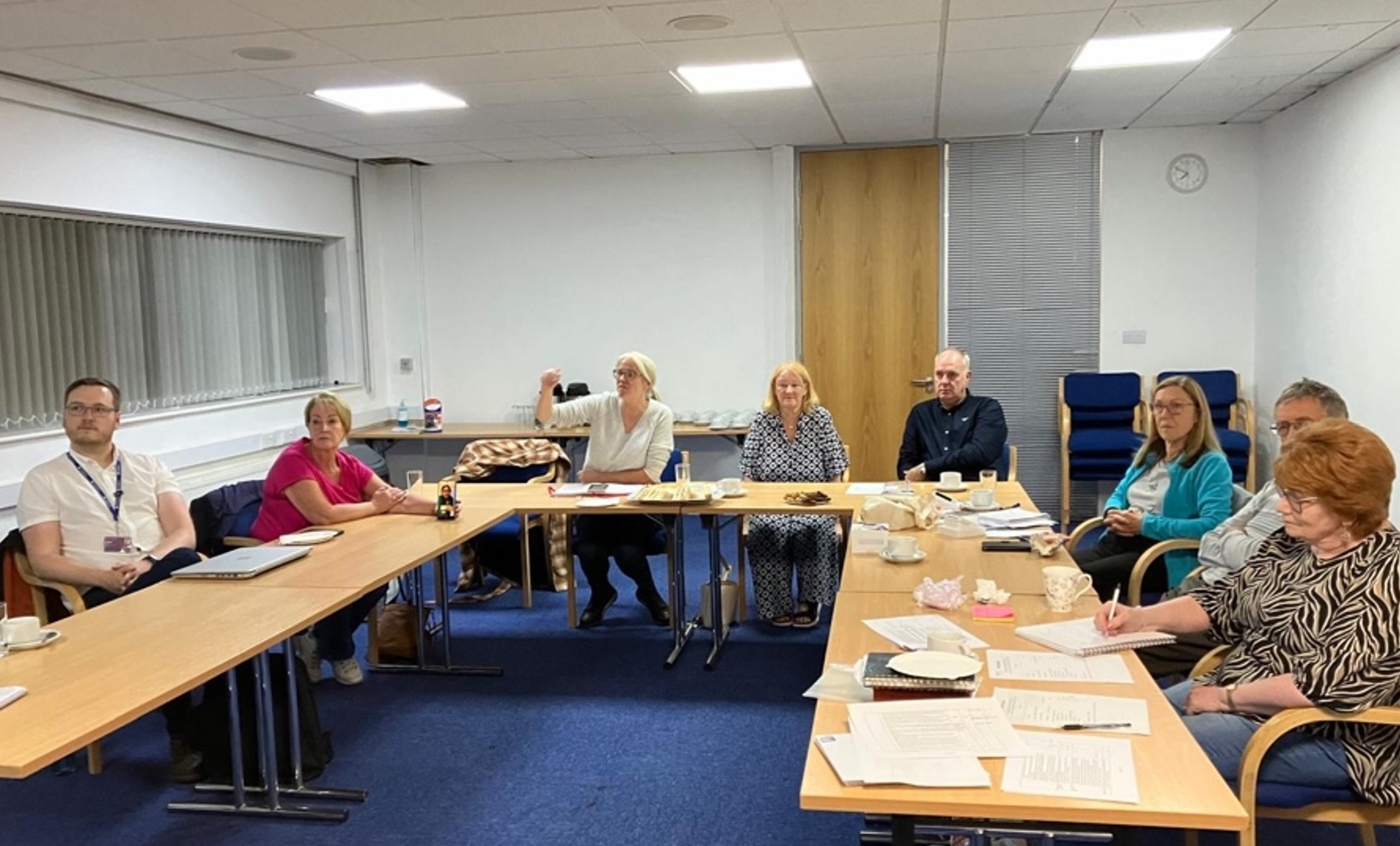 Wirral branch volunteers sat at a u shaped table in a meeting room